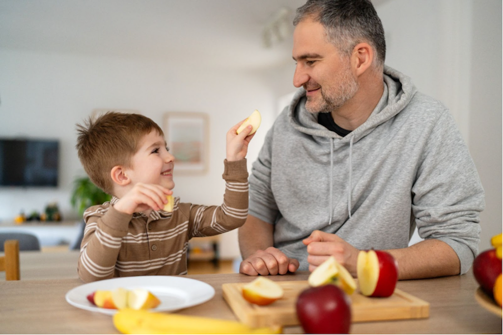 Images of father and son eating apples, Mini quiches, hummus and vegetable plate, and chicken fajitas on a cooking sheet.  